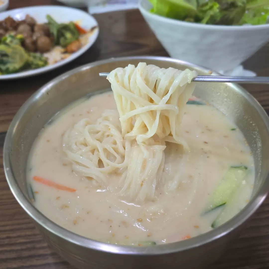 Close-up of Kongguksu noodles being lifted by chopsticks