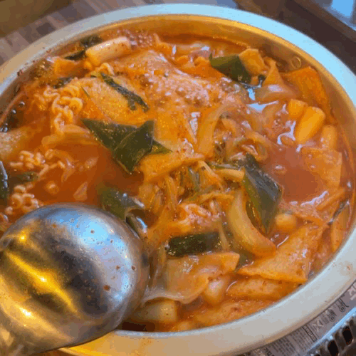 Tteokbokki simmering on a portable burner at the table