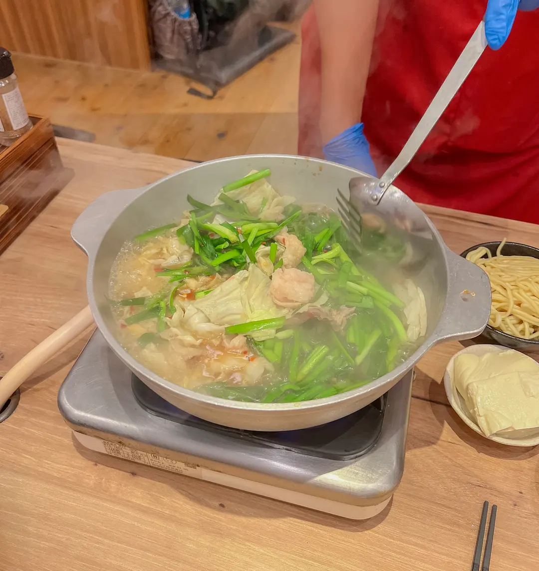 A close-up of the Motsunabe ingredients, showing the texture of the offal and fresh vegetables.