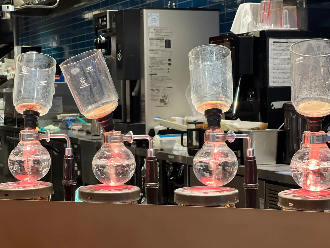 A close-up of a siphon coffee maker in action, highlighting the unique brewing process at Kurashiki Coffee.