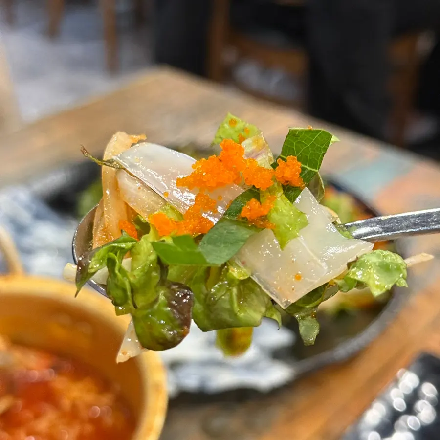 Preparing a bite of cuttlefish sashimi with vegetables