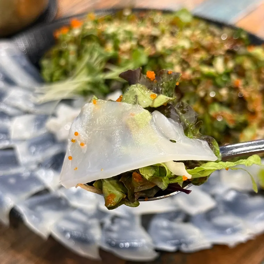 A perfect bite of cuttlefish sashimi and salad
