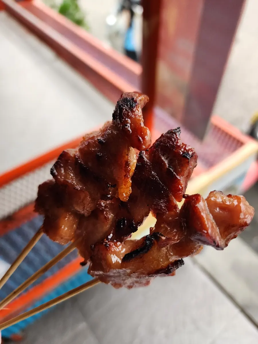 Hand holding Mu Ping skewers with sticky rice