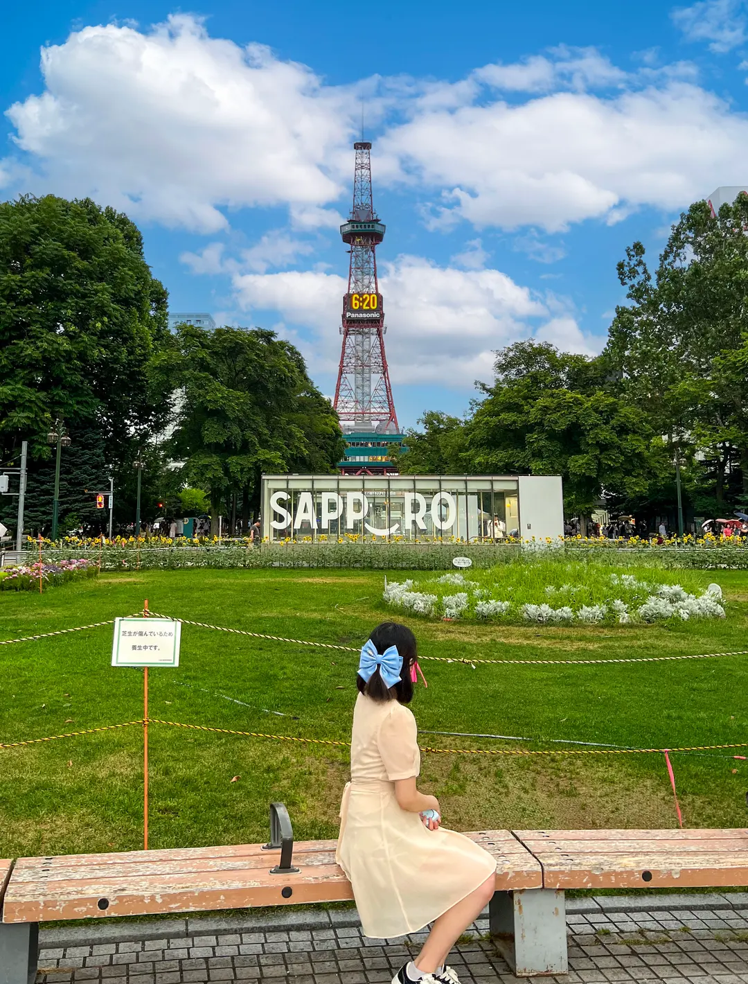 A woman in a light summer dress walking through a park in Sapporo.