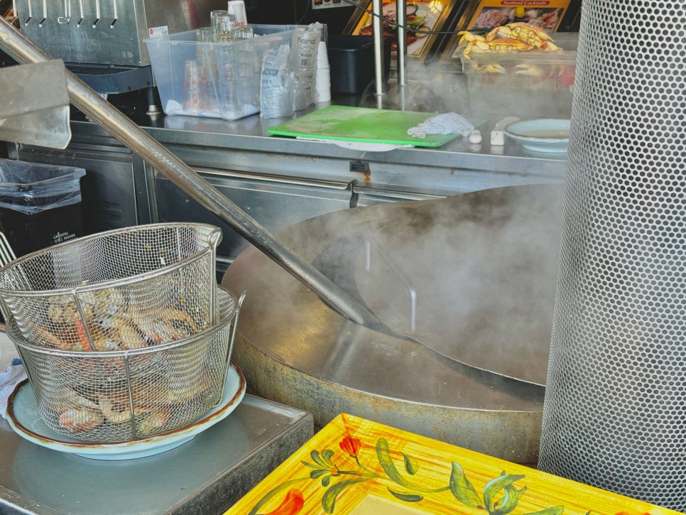 An open-air kitchen with chefs preparing fresh seafood.