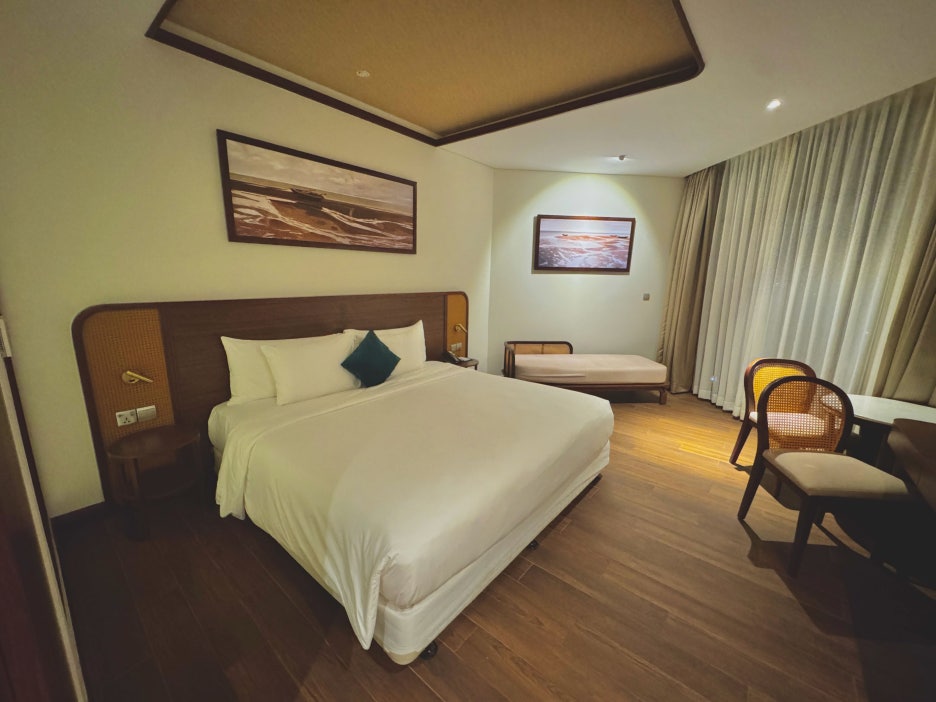 Spacious hotel room with a king-size bed and a small sofa.