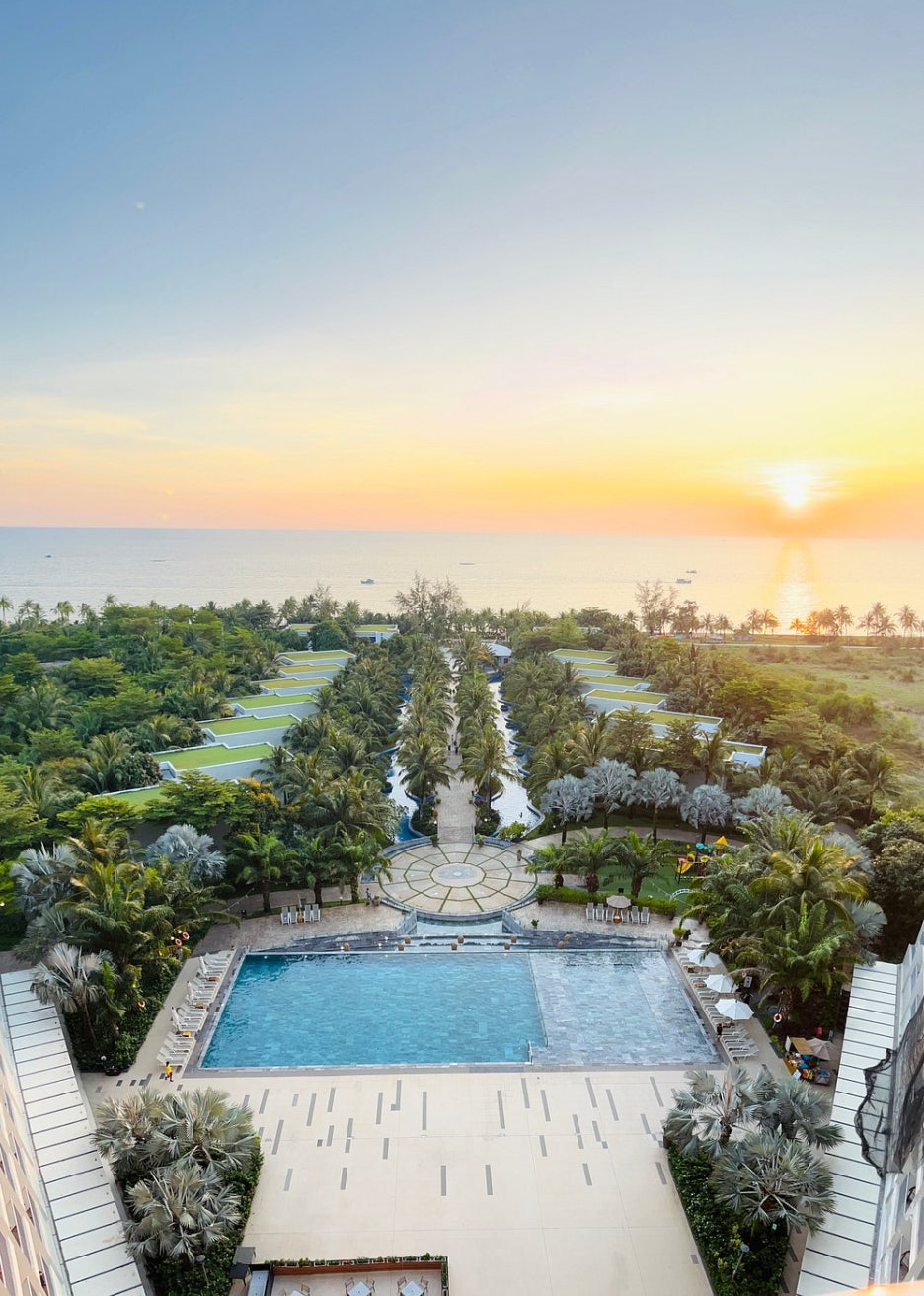 A panoramic view of the massive lagoon-style pool, resort villas, and the beach in the distance.
