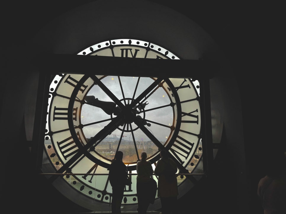 The iconic clock face on the 5th floor of the Musée d'Orsay, with a silhouette of a person looking out over Paris.