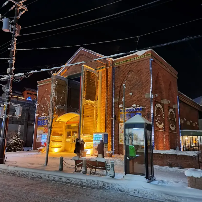 Hakodate Beer 函館啤酒廠外觀,被白雪環繞,燈光溫暖。